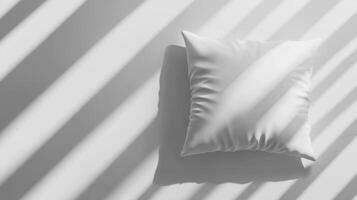 Soft pillow rests on a surface bathed in light and shadow patterns photo