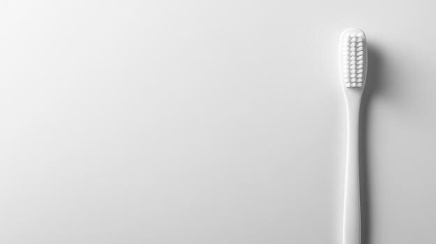 Simple white toothbrush resting on a clean surface in bright light photo