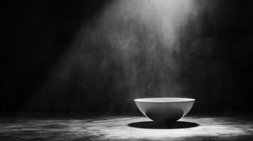 Light illuminates a minimalist bowl in a darkened space photo