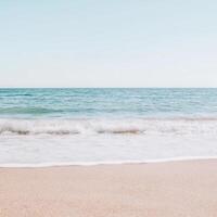 Gentle waves lap against the sandy shore at serene beach setting photo