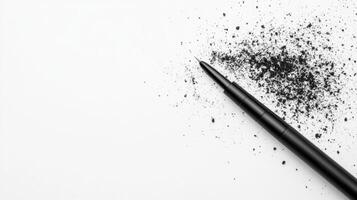 Black pencil resting beside graphite shavings on white paper photo
