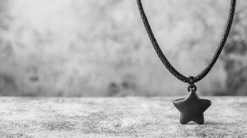 Star pendant hanging from a black cord on a textured surface photo