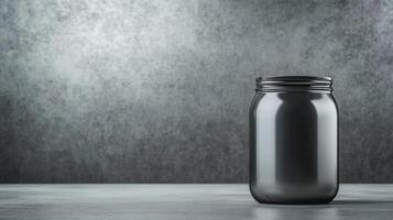Glass jar with black lid set against a textured gray background photo
