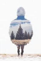 Person standing in a forest landscape silhouette with cloudy sky photo