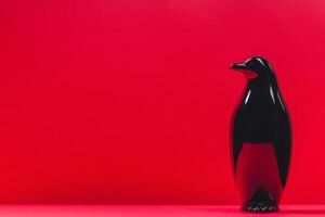 Black penguin figurine on bright red background creating contrast photo