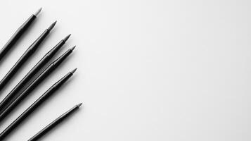 Collection of black pens arranged neatly on a white surface photo