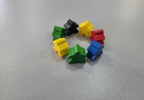A circle of colorful wooden men on a gray background Small figures of toy wooden colorful men photo