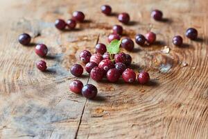 Fresh cranberries placed on a rustic wooden table with a shallow depth of field, highlighting the vibrant red color and texture of the berries photo