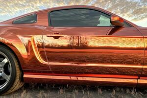 Sleek modern car parked in the middle of a vast open field, surrounded by nature and wide open space photo