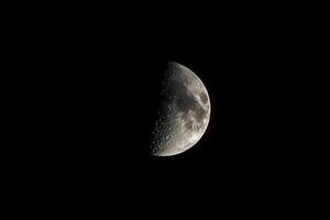 A close-up view of the moon's surface, revealing intricate details of craters and lunar texture, illuminated by the night sky photo