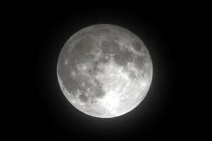 A black and white image of the full moon shining brightly in the dark night sky, creating a dramatic and peaceful atmosphere photo
