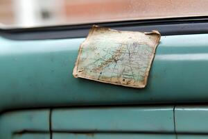 A close-up of an old, vintage map placed on a car window, capturing a nostalgic, timeless travel vibe photo