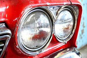 A close-up shot of the headlight of a vintage red car, showcasing its intricate details and classic design photo