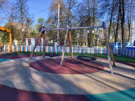Children's wooden empty swing with a round rope seat in a children's park photo
