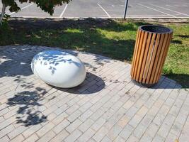 On a beautiful sunny day, in a shady garden, next to a trash can, there is one white decorative concrete oval photo