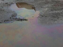 A large rainbow puddle of spilled petroleum product on the road The concept of environmental pollution photo