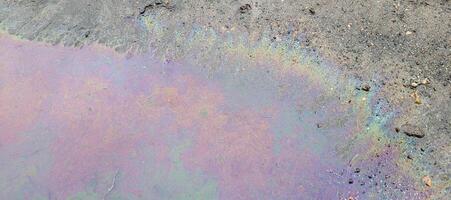A rainbow puddle of spilled petroleum product on the road. The concept of environmental pollution photo