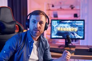 A man is sitting in front of a computer with headphones on photo