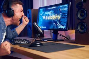 A man is sitting in front of a computer with headphones on photo