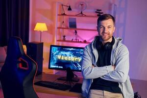 A man sitting in front of a computer with a gaming chair photo
