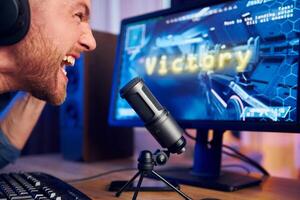 A man is screaming into a microphone while playing games photo