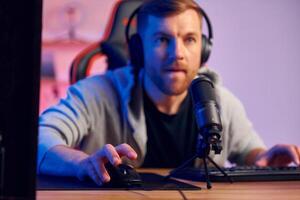 A man in headphones is sitting at a desk with a microphone photo