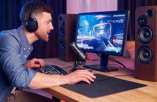 A man wearing headphones is playing a game on a computer photo
