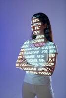A woman standing in front of a wall with a lighted up text photo