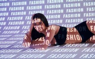 A woman laying on a bed with the words fashion on the wall photo