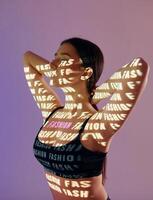 A woman in a bra top with words projected on her body photo