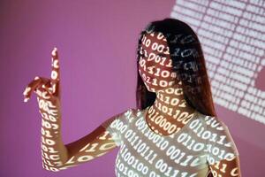 A woman is holding up a finger with binary code projected on it photo