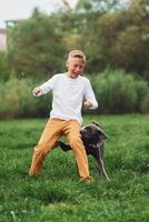A boy playing with a dog in a field photo