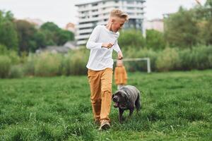 A boy running with a dog in a field photo