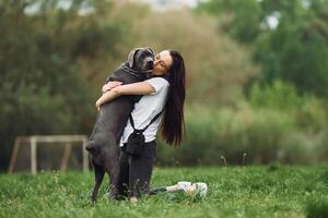 A woman is hugging a large dog in a field photo