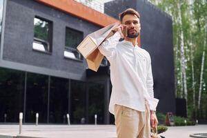 A man is holding a shopping bag and talking on the phone photo