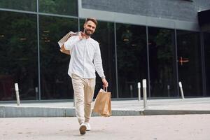 A man walking with shopping bags and talking on his phone photo