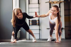 Two women doing push ups in a gym photo