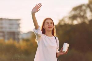 Greetings gesture.. Young girl is on the field at sunny daytime having nice weekend photo