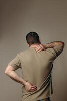 man suffers from back pain due to negative impact of long work at computer, bad posture, uncomfortable work place. Concept of comfortable work space to avoid joint pain and health problems photo