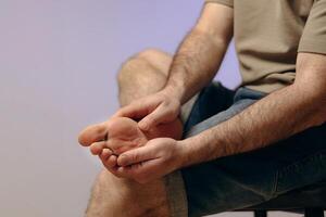 Man holding his leg with his hand, experiencing pain or discomfort. Concept of plantar fasciitis, bruises, stress fractures due to prolonged use, improper footwear or intense training. photo