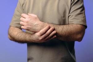 A man holds his wrist in pain. The hand tightly clasps the affected area, emphasizing the soreness and need for support. Pain and suffering in the wrist interfere with professional activities. photo