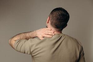 man suffers from back pain due to negative impact of long work at computer, bad posture, uncomfortable work place. Concept of comfortable work space to avoid joint pain and health problems photo