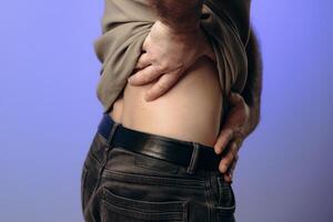man experiences back neck pain due to age-related changes, osteochondrosis, herniated discs or chronic spinal diseases. Prevention of spinal problems, therapeutic exercises, physiotherapy. photo