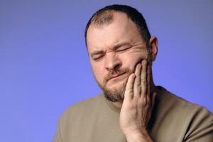 man holding his cheek with his hand experiencing severe toothache. Toothache is the most severe pain in a person. Teeth require careful care. They play an important role in a person's life photo