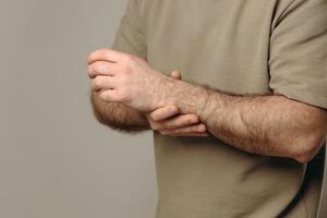 A man holds his wrist in pain. The hand tightly clasps the affected area, emphasizing the soreness and need for support. Pain and suffering in the wrist interfere with professional activities. photo