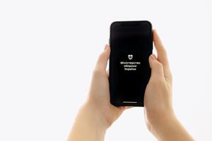 Zaporizhia, Ukraine - January 10, 2025. A woman holds an iPhone with the Reserv plus app logo on the screen while using a mobile app for business at home. white background photo