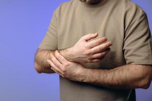 A man holds his wrist in pain. The hand tightly clasps the affected area, emphasizing the soreness and need for support. Pain and suffering in the wrist interfere with professional activities. photo