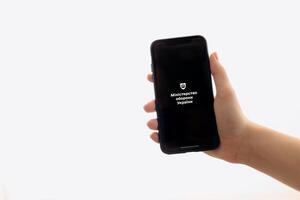Zaporizhia, Ukraine - January 10, 2025. A woman holds an iPhone with the Reserv plus app logo on the screen while using a mobile app for business at home. white background photo