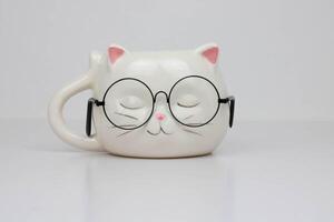 Funny white cup in the shape of a cat's head with round glasses. photo