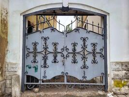 The arch of the house has a grey iron gate with wrought iron elements photo